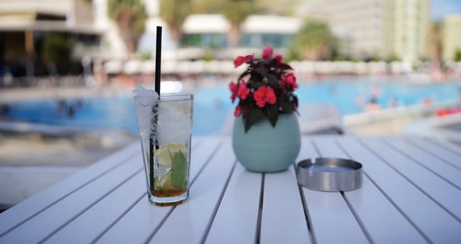 Lemonade and soft drinks in glass with ice. Summer cocktails drink on table by pool