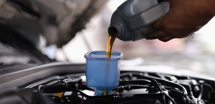 Mechanic pouring engine oil into engine in car service. Services and auto repair shop business concept