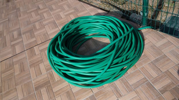 Green twisted garden hose in garden. Watering system and choosing a quality garden hose