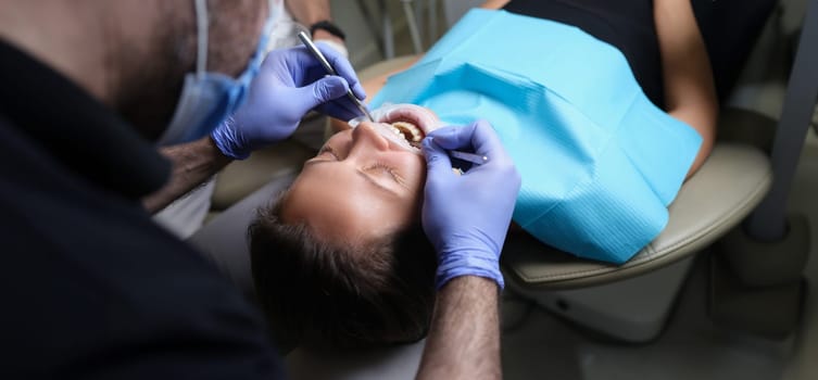 Dentist treats teeth with caries to female patient in dental clinic. Care and treatment of teeth concept