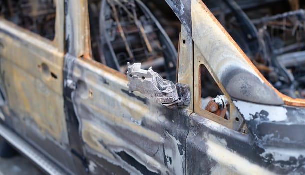 Door of burned-out car on street closeup. Riot civil protest and crime in city. Explosion fire result and car insurance concept