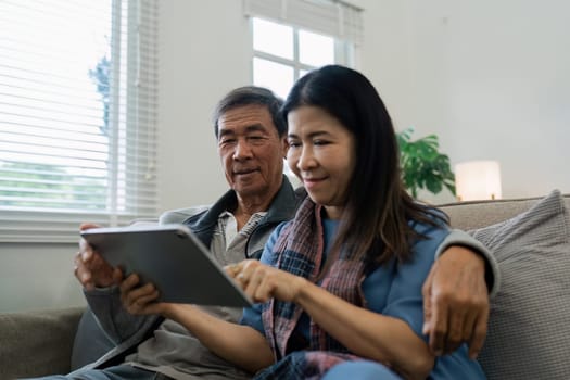 Smiling caucasian senior elderly couple grandparent using tablet together.