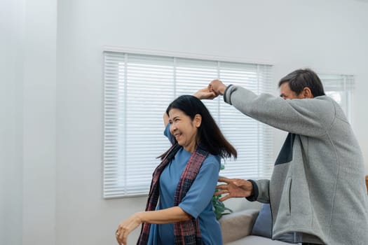 Happy cheerful middle aged mature couple family parent dancing together in the living room.