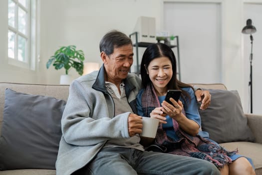 Smiling caucasian senior elderly couple grandparent using mobile together.