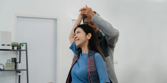 Happy cheerful middle aged mature couple family parent dancing together in the living room.