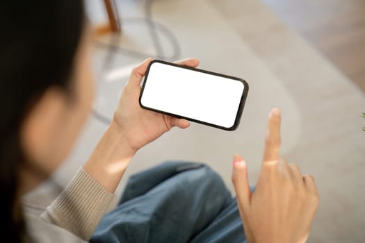 Mockup smartphone of a woman holding and using mobile phone with blank screen while on the sofa with feeling relaxed.