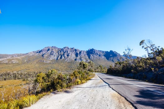 The picturesque Gordon River Rd at the Sentinel range of mountains near Bitumen Bones Sculpture on a hot summer's afternoon in Southwest National Park, Tasmania, Australia