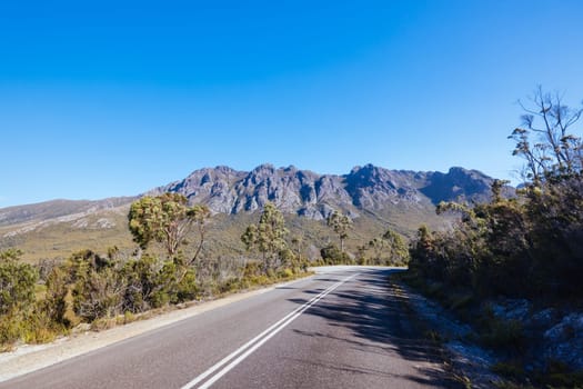 The picturesque Gordon River Rd at the Sentinel range of mountains near Bitumen Bones Sculpture on a hot summer's afternoon in Southwest National Park, Tasmania, Australia