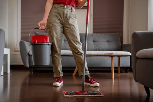 Housewife Stands With Mop In Room, Close-Up Of Face Not Visible