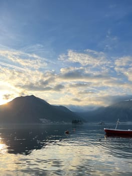 Fishing boat in the sea against the backdrop of a mountain range and sunset sky. High quality photo