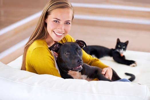 Woman, pets and relax on sofa in portrait, smile for dog and cat love with bonding at home. Happy, positive and trust with foster or adoption, cuddle puppy in living room and domestic animal care.