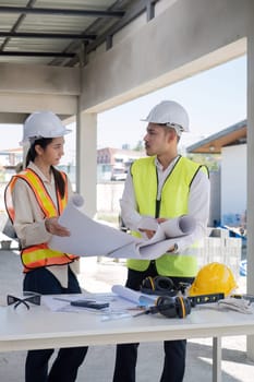 Civil engineer teams meeting working together wear worker helmets hardhat on construction site in modern city. Foreman industry project manager engineer teamwork. Asian industry professional team.