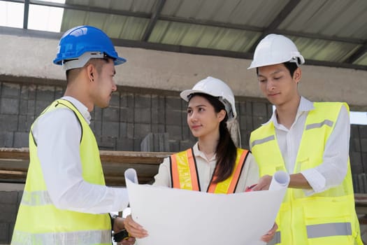 Civil engineer teams meeting working together wear worker helmets hardhat on construction site in modern city. Foreman industry project manager engineer teamwork. Asian industry professional team.