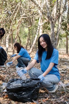 A group of Asian volunteers collects trash in plastic bags and cleaning areas in the forest to preserve the natural ecosystem..