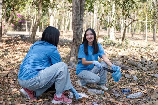 A group of Asian volunteers collects trash in plastic bags and cleaning areas in the forest to preserve the natural ecosystem..