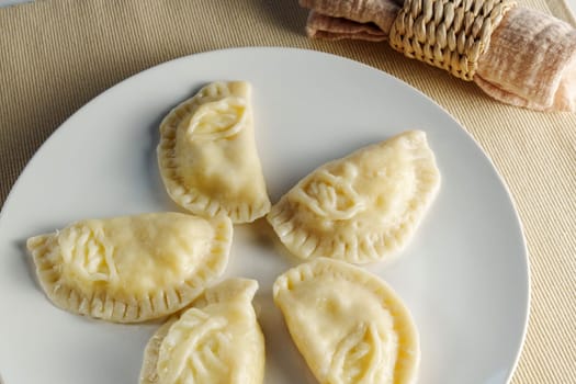 Elegance of perfectly crimped crescent dumplings, or ravioli, presented on a white plate, ready to entice any food connoisseur.