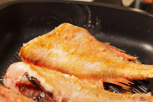 Fresh sea bass sizzles to perfection in a hot skillet, showcasing a delightful evening feast in the making.