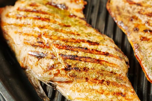 Salmon fillets sizzle and cook to perfection on a grill, infusing the air with a tantalizing aroma
