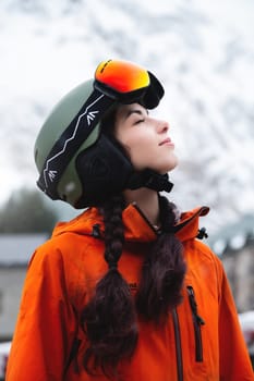A young woman of Caucasian ethnicity looks to the side and smiles, raising her head to the sky, enjoying her vacation at the ski resort