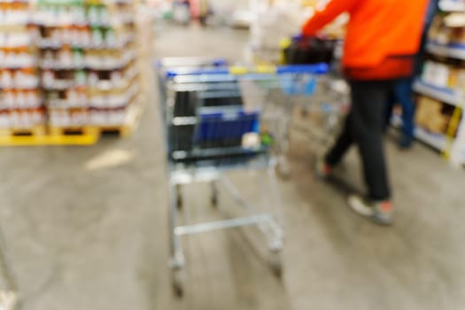 Blurry shot of a shopping cart in a busy store aisle, showcasing the hustle and bustle of shopping activities.