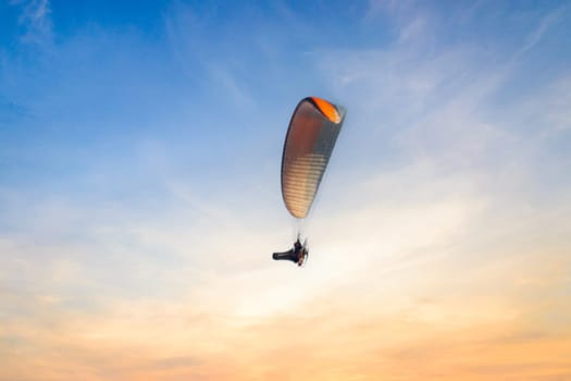 Motor Paraglider flying over the surface of the water in the evening. High quality photo