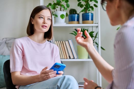 Young woman patient at meeting session with female psychologist therapist social worker counselor psychotherapist. Mental health professional help support treatment psychology psychotherapy counseling