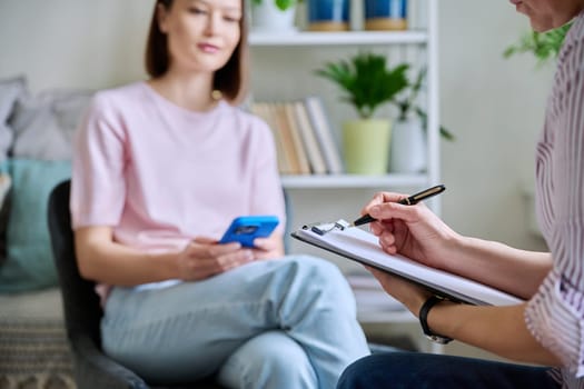 Close up of clipboard hands of female psychologist therapist psychotherapist counselor, meeting therapy with young female patient. Mental health professional help support treatment counseling