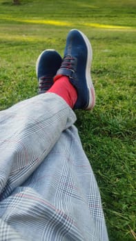legs in trousers and sneakers on green grass. High quality photo
