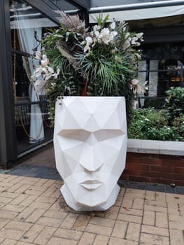 creative outdoor planter in the shape of a human head with flowers instead of hair.