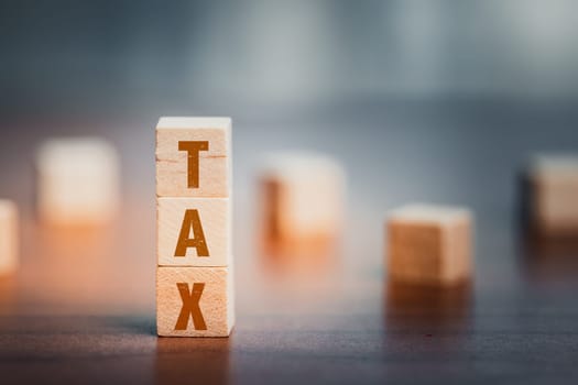 Wooden cubes with the word TAX on a desk, encapsulates a business concept related to financial responsibilities, accounting, and fiscal considerations.