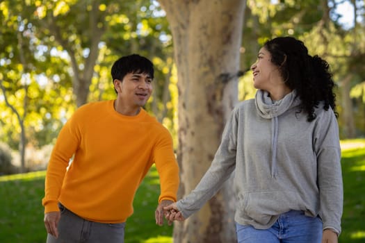 Happy woman and boyfriend holding hand in a park.Couple having fun together with love.