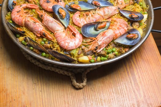 Traditional Spanish paella full of seafood on a wooden stand in a kitchen setting, typical Spanish cuisine, Majorca, Balearic Islands, Spain.