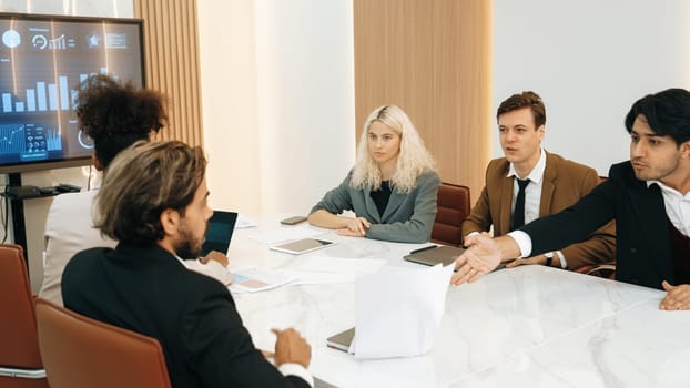 Analyst team utilizing BI Fintech to analyze financial data at table in ornamented meeting room. Businesspeople analyzing BI dashboard power for business insight and strategic marketing planning.