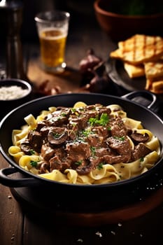 Savory beef stroganoff served over noodles garnished with parsley, paired with bread and beer.
