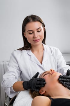 Young cosmetologist woman doing hydra facial treatment for young woman in a beauty salon.