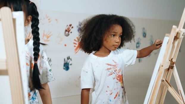 Happy creative african girl painted or draw canvas together with asian boy. Group of playful student create funny painting or artwork painted by watercolor. Creativity activity concept. Erudition.