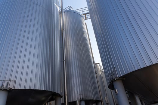 Brewery silos or tanks typically use for storing barley or fermented beer. Outdoor brewery equipment with stainless steel tanks and pipes.