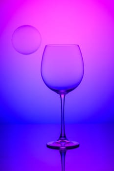 wine glass with soap bubbles on blue and pink background 1