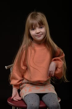 studio portrait of a charming little girl on a black background