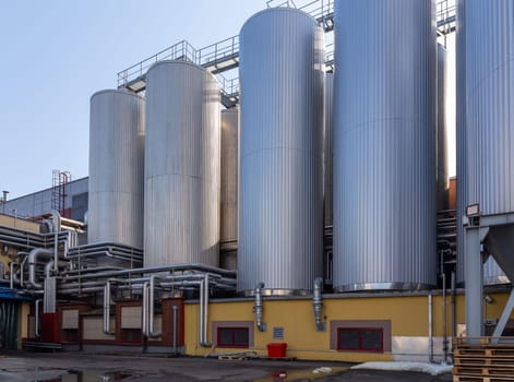 Brewery silos or tanks typically use for storing barley or fermented beer. Outdoor brewery equipment with stainless steel tanks and pipes.