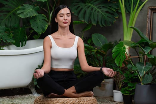 Young woman doing morning yoga and meditation in natural garden with plant leaf, enjoying the solitude and practicing meditative poses. Mindfulness activity and healthy mind lifestyle. Blithe