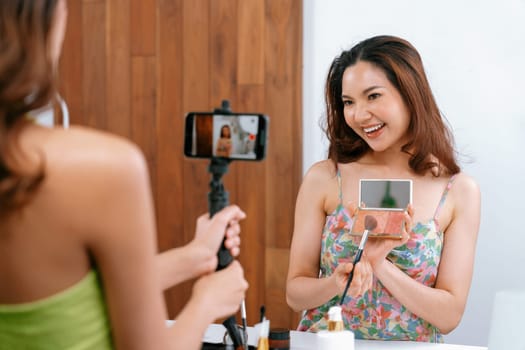 Asian Woman influencer shoot live streaming vlog video review makeup uttermost social media or blog. Happy young girl with cosmetics studio lighting for marketing recording session broadcasting online