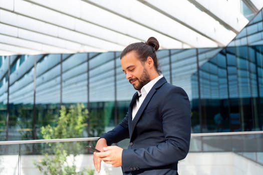 Businessman standing outdoor use smartphone looking device screen confident. Handsome hispanic male business person middle age dressed business suit holding smartphone in hand. Modern business person