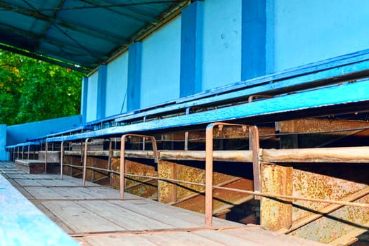 Old grandstand seats. Vintage tone. Old blue wooden grandstand stadium.