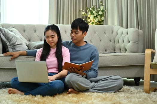 Happy married young couple using laptop, spending weekend time together at home.