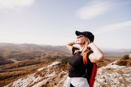 woman on mountain peak looking in beautiful mountain valley in autumn. Landscape with sporty young woman, blu sky in fall. Hiking. Nature.