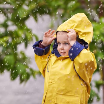 Happy, boy and rain jacket in winter with thinking for carefree, childhood and enjoyment in Germany. Kid, smile and wondering in nature for vacation, weekend or holiday travel in cold weather.