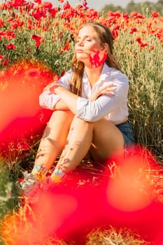 Woman poppies field. Happy woman is resting in the rays of the sun sitting in the poppy field