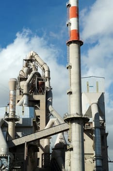 pipes of a cement plant against the background of a cloudy sky close up