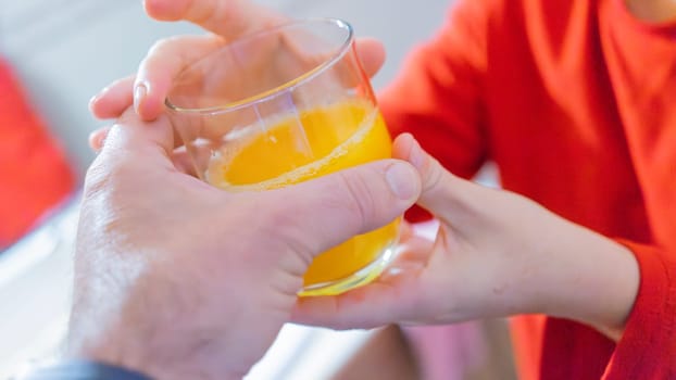 Close-up of hands exchanging a glass filled with fresh orange juice